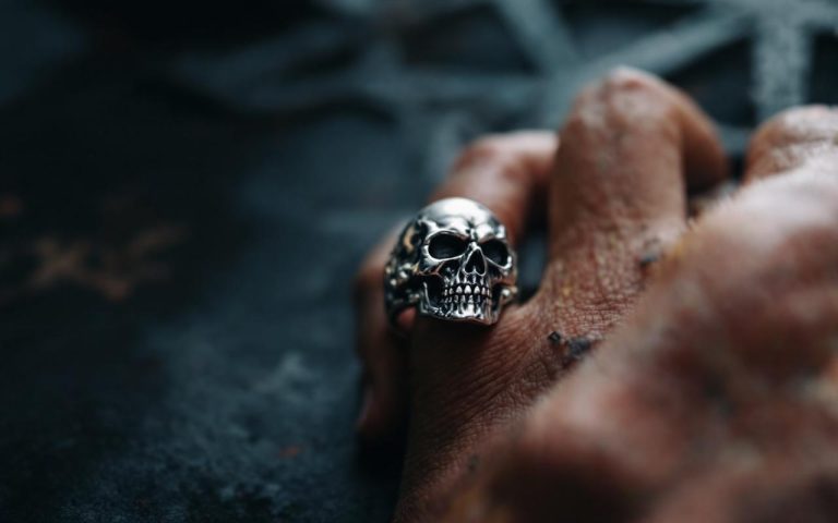 une-main-portant-une-bague-en-forme-de-crane-mettant-en-valeur-les-details-du-bijou-et-la-texture-de-la-peau-dans-un-environnement-avec-un-eclairage-doux