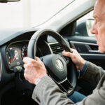 Comment réagir au message injection à contrôler avant un long trajet ? Intérieur d’une voiture moderne en plein jour : le conducteur, un homme d’âge moyen, paraît préoccupé en observant le tableau de bord avant de démarrer et de partir sur la route.
