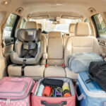 Équipements voiture famille : 8 essentiels pour les trajets Habitacle familial lumineux et bien organisé, avec deux sièges enfants, des rangements pratiques et des bagages soigneusement disposés dans le coffre ouvert.