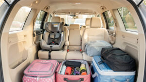 Habitacle familial lumineux et bien organisé, avec deux sièges enfants, des rangements pratiques et des bagages soigneusement disposés dans le coffre ouvert.