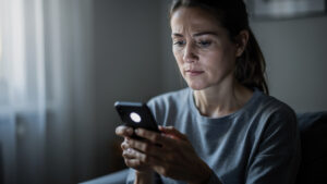 Femme consultant un smartphone après avoir remarqué un appel manqué, dans une ambiance intérieure réaliste et sobre.